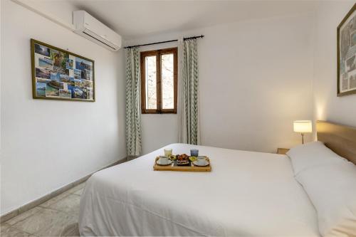 a white bedroom with a bed with a tray of food on it at Flat in the old town of Alcudia in Alcudia