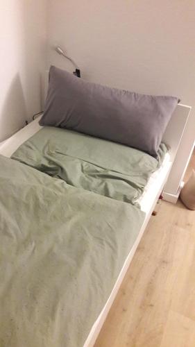 a bed with green sheets and a pillow on it at Familie Vietzke in Hannover