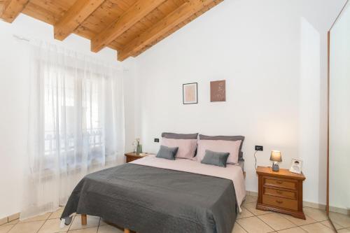 オージオ・ソットにあるAPPARTAMENTO PORTA VERDEの白いベッドルーム(大型ベッド1台付)と木製の天井が備わります。