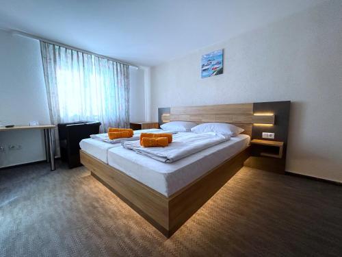 um quarto com uma cama grande e almofadas laranja em Hotel Schäffer - Steakhouse Andeo em Gemünden