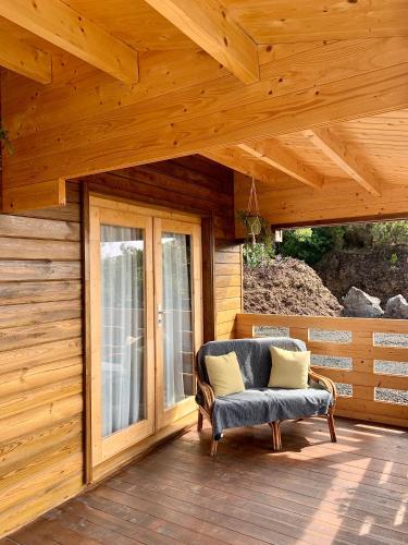 a porch of a wooden cabin with a chair and a window at PicoTerrace View in Madalena