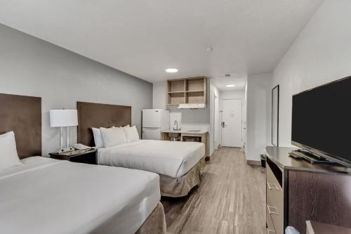 a hotel room with two beds and a flat screen tv at Clarion Inn Salt Lake City Airport in Salt Lake City