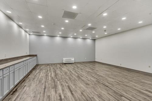 an empty room with white walls and wooden floors at Clarion Inn Salt Lake City Airport in Salt Lake City