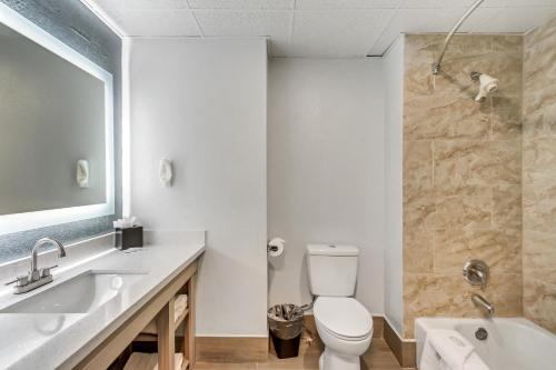 a bathroom with a toilet and a sink and a tub at Clarion Inn Salt Lake City Airport in Salt Lake City