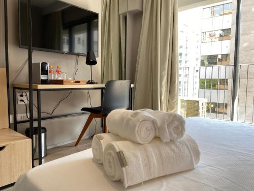 a room with towels on a bed with a desk at Studio Completo na Haddock Lobo in São Paulo