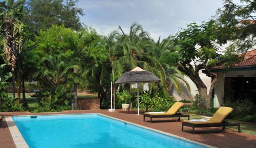 a swimming pool with two chairs and an umbrella at Cresta Bosele Hotel in Selebi-Pikwe