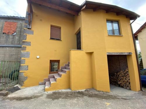 ein gelbes Haus mit seitlicher Treppe in der Unterkunft La Casucha in Caboalles de Abajo