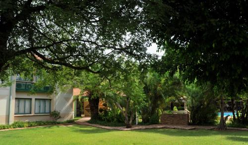 a house with a tree in front of a yard at Cresta Bosele Hotel in Selebi-Pikwe