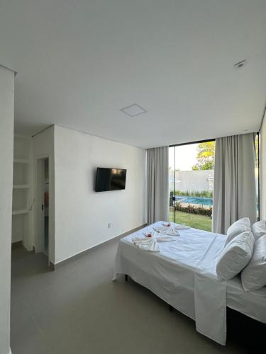 a white bedroom with a bed and a large window at Cantinho do sossego in Porto Seguro