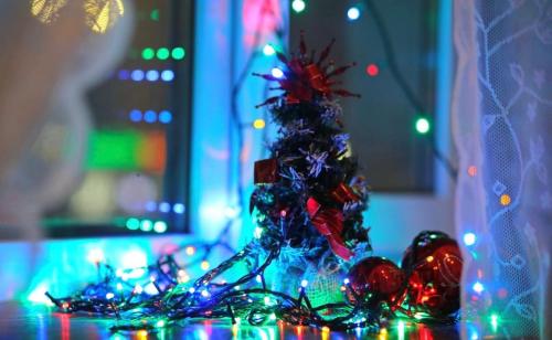 een kerstboom zittend op een tafel met lichten bij VIP apart 364 in Tbilisi City