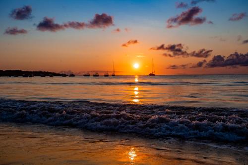 a sunset on the beach with boats in the water at Garapua Praia Hotel in Garapuá