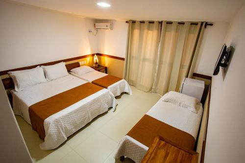a hotel room with two beds and a window at Garapua Praia Hotel in Garapuá