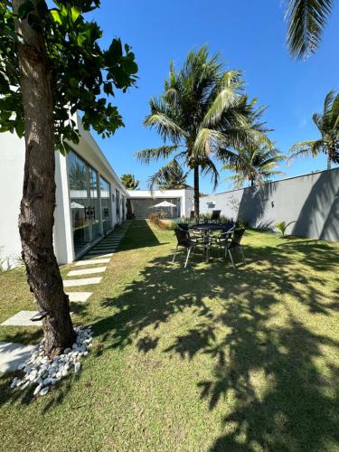 a table and chairs in a yard with palm trees at Cantinho do sossego in Porto Seguro
