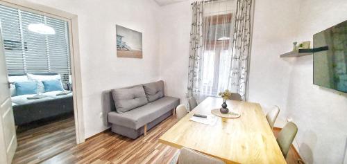 uma sala de estar com uma mesa e uma cadeira em Dora Holiday House & Apartments em Keszthely