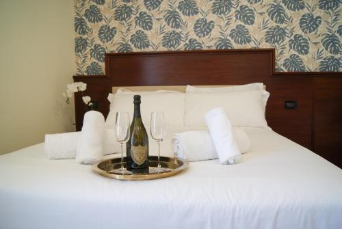 a bed with a bottle of wine and two glasses at Glam Luxury Rome in Rome