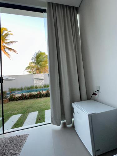 a room with a window with a view of a palm tree at Cantinho do sossego in Porto Seguro