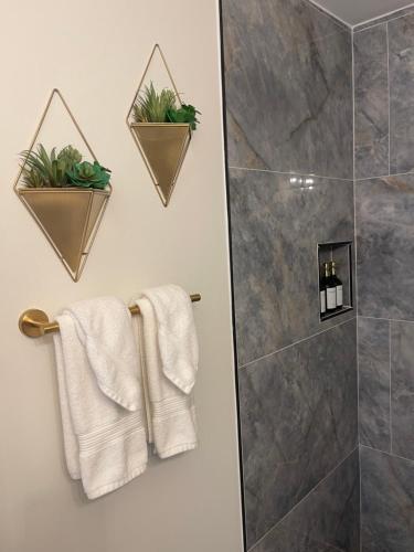 La salle de bains est pourvue d'une douche, de serviettes et de plantes. dans l'établissement Mirabelle 3bd/1ba 5 min from Downtown/Duke/RTP, à Durham