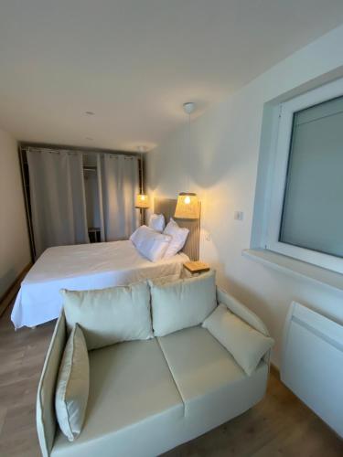 1 dormitorio con cama blanca y sofá en Les petites plumes d’Hag, en Haguenau