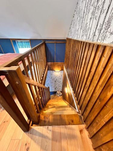 a room with a bed and a wooden staircase at La Grange Aux Hirondelles - Chambre familiale in Woignarue