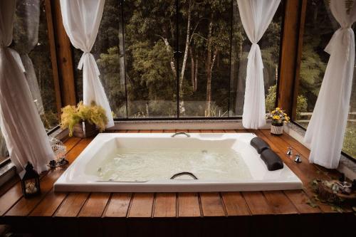 a bath tub in a room with a window at Chalé Caminho do Sol in Rancho Queimado