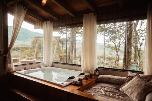 a bath tub in a room with a large window at Chalé Caminho do Sol in Rancho Queimado