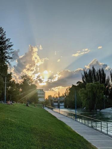 a sunset in a park with a sidewalk and grass at Depto en Roca 2 in General Roca