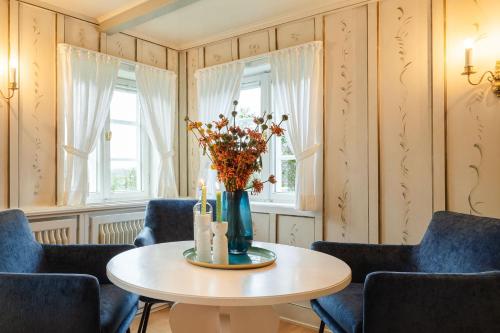 una stanza con tavolo, sedie e vaso di fiori di Bullerbü im Uthland a Braderup