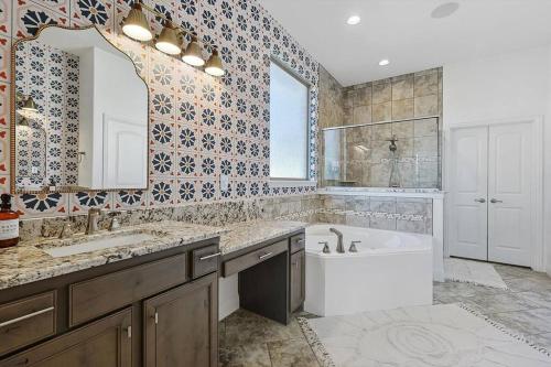 La salle de bains est pourvue d'une baignoire, d'un lavabo et d'un miroir. dans l'établissement Modern Olympus View Oasis + Pool, à Waxahachie