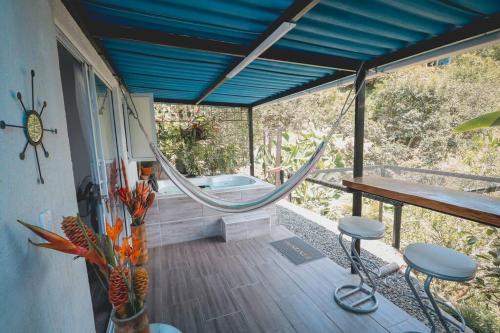 a porch with a hammock and a bath tub at Cabaña / hotel campestre en Manizales para pareja in Manizales