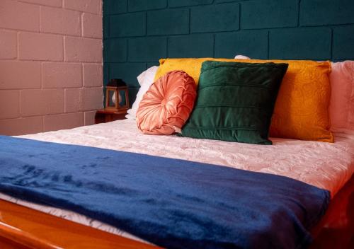 a bed with colorful pillows on top of it at Lolas Hostal Hab. doble (baño privado) in San José