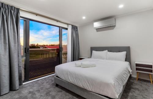 een slaapkamer met een bed en een groot raam bij The Antilia in Auckland