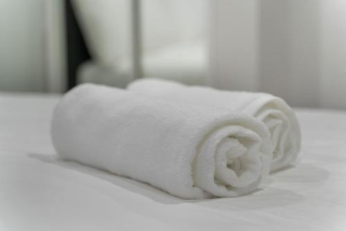 een stapel witte handdoeken bovenop een bed bij The Antilia in Auckland