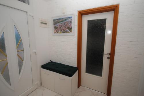 a bathroom with a toilet and a door with a green seat at Apartman Alchemist I in Bosanska Dubica