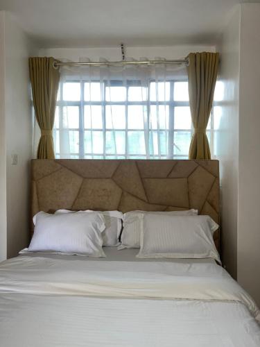 een bed met witte kussens en een groot raam bij Kasha Homes in Muyaka