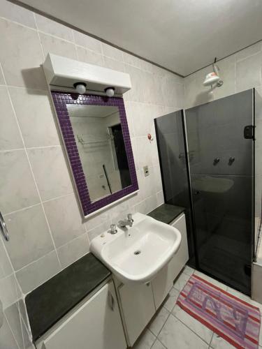 a bathroom with a sink and a shower and a mirror at Flat Paladium in São Vicente