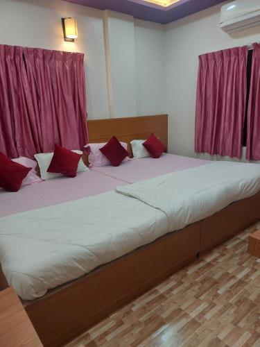a large bed with red pillows in a room at Hotel Sai Dakshina Inn & The Fern Restaurant in Shirdi
