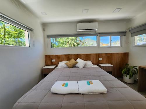 a bedroom with a large bed and two windows at Casa de Campo Flor Dorada in Centenario