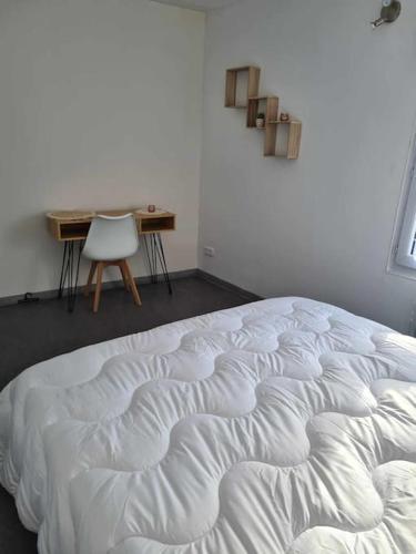 a white bed in a room with a desk and a chair at Logement agréable in Fauquembergues
