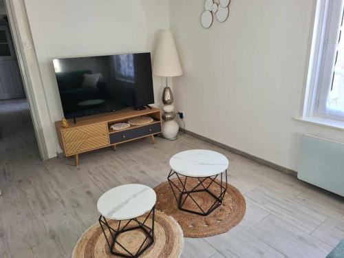 - un salon avec deux tables et une télévision dans l'établissement Logement agréable, à Fauquembergues