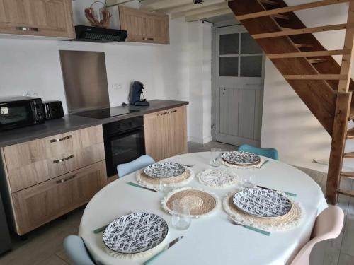 a kitchen with a white table with four plates on it at Logement agréable in Fauquembergues