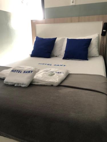 a bed with blue and white pillows on it at Hotel sany - Localizado à 5 minutos do Metrô Paulista in São Paulo