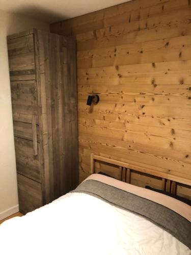 une chambre avec un lit et un mur en bois dans l'établissement Appartement 2 chambres centre MORZINE, à Morzine