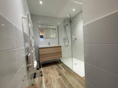 ein weißes Bad mit einer Dusche und einem Waschbecken in der Unterkunft Maison 8 pers 1 minute parc des expositions in Bohars
