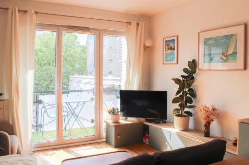 a living room with a tv and a large window at Crossing cocoon with balcony and clear view in Paris