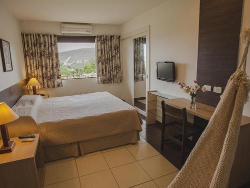 um quarto de hotel com uma cama, uma secretária e uma televisão em Portal de Gravatá em Gravatá