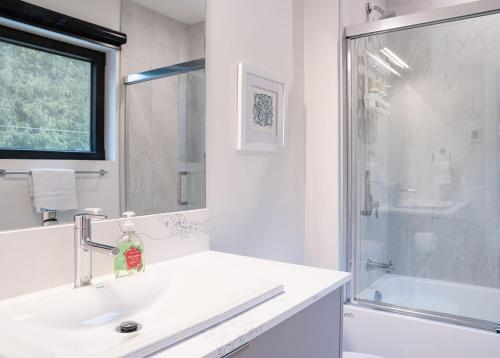 a white bathroom with a sink and a shower at Hemlock Hangout by Revelstoke Vacations in Revelstoke