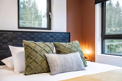 a bedroom with a bed with pillows and windows at Hemlock Hangout by Revelstoke Vacations in Revelstoke