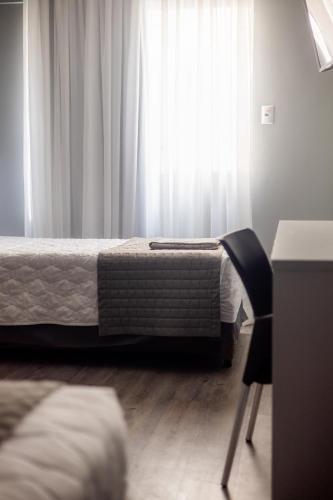 a bedroom with a bed and a window with curtains at Hotel Negrini in Balneário Camboriú