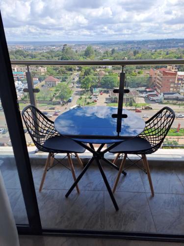 a table and chairs on a balcony with a view at Cozy 2 bedroom apartment With gym &washer near yaya centre in Nairobi