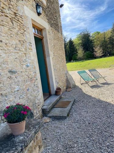 un bâtiment en pierre avec une porte, une table et des fleurs dans l'établissement Maison confortable et calme, 2 chambres, à Saint-Marcel-Bel-Accueil